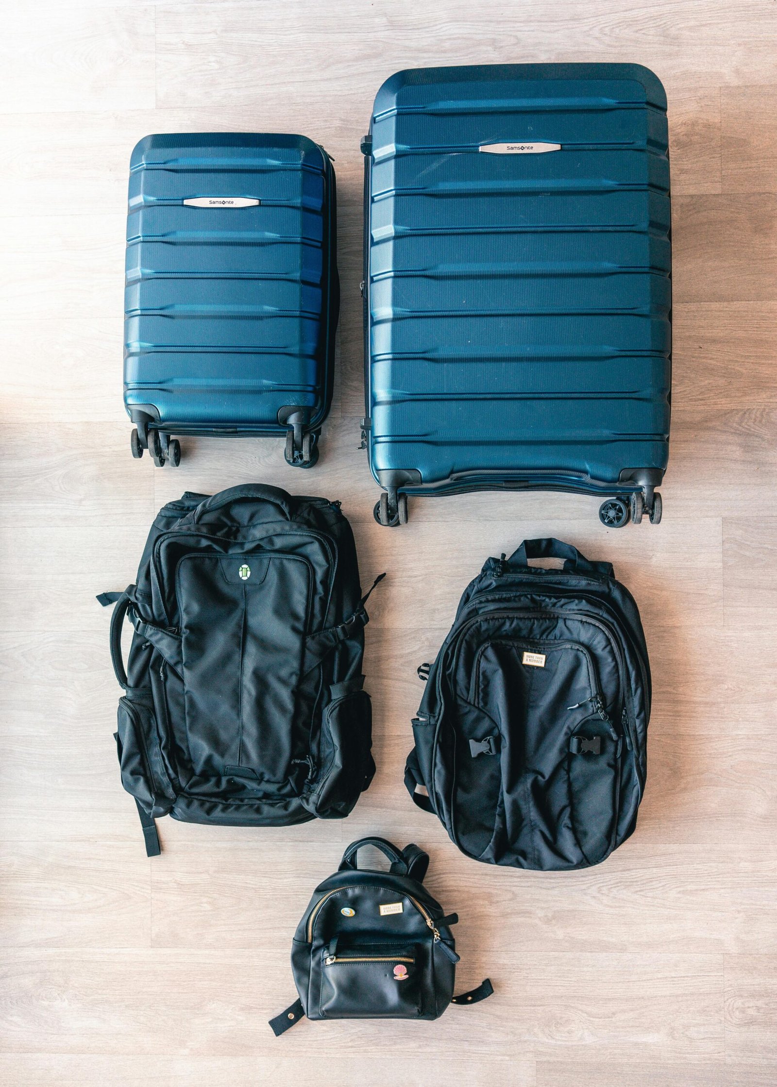 Aerial view of modern luggage and backpacks arranged on a wooden floor.